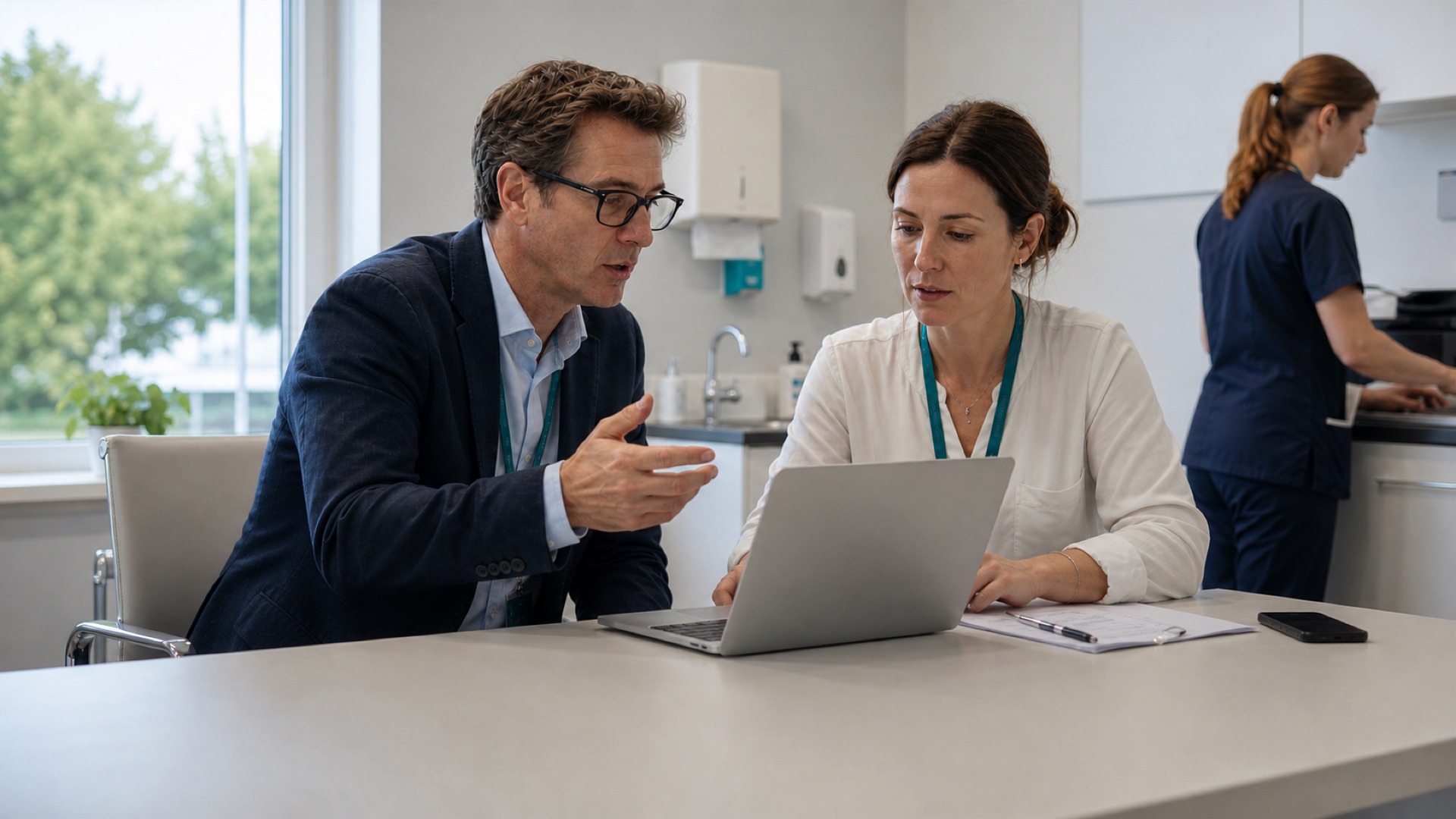 A male consultant and female clinician reviewing patient work together in a bright private clinic